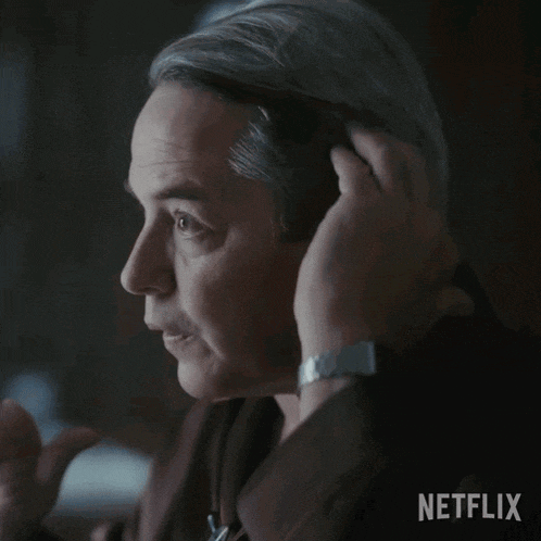 a man adjusts his ear buds with a netflix logo behind him