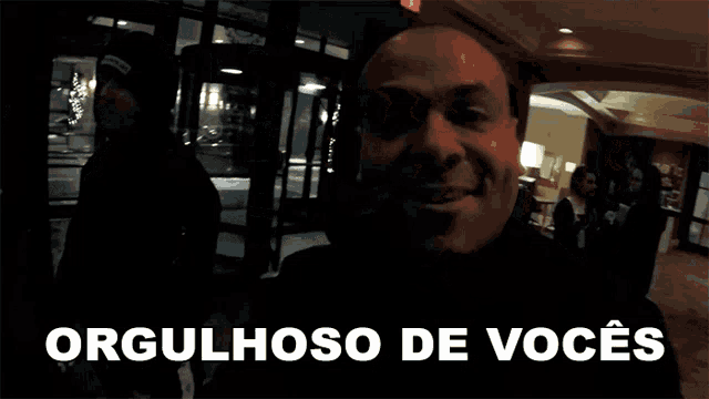a man is smiling in front of a sign that says " orgulhoso de voces "