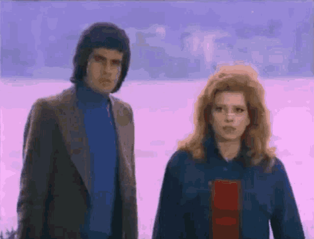 a man and a woman are standing next to each other in a field