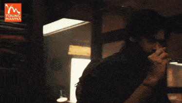a young man smoking a cigarette in a dark room