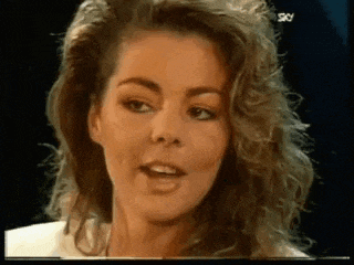 a close up of a woman 's face with curly hair and a white shirt .