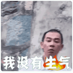 a man is standing in front of a wall with chinese writing behind him .