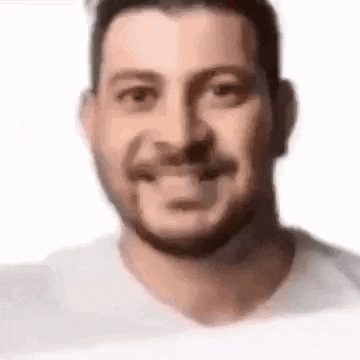 a close up of a man 's face with a beard and mustache smiling .