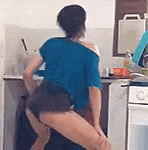 a woman in a blue shirt and shorts is dancing in the kitchen .