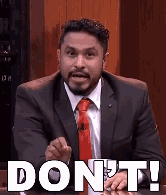 a man in a suit and tie says " do n't " while sitting at a table