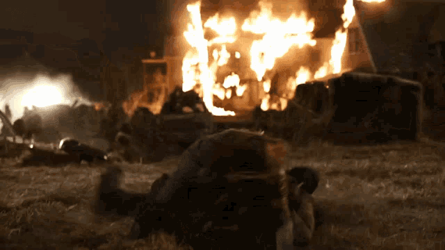 a man is laying on the ground in front of a burning house