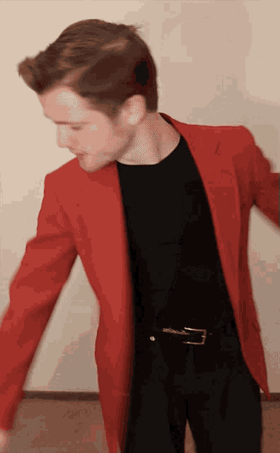 a man wearing a red jacket and a black shirt is dancing