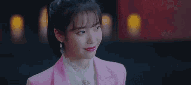 a close up of a woman wearing a pink suit and white shirt .