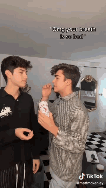 two boys are standing next to each other and one of them is holding a can of aguila