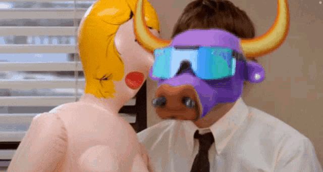 a man wearing a purple bull mask kisses a naked woman