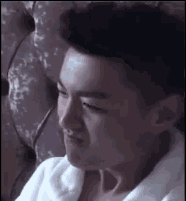 a man wearing a white robe is sitting on a couch making a funny face .
