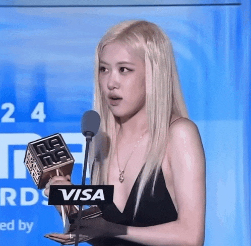 a woman in a black dress holds a trophy in front of a microphone that says visa