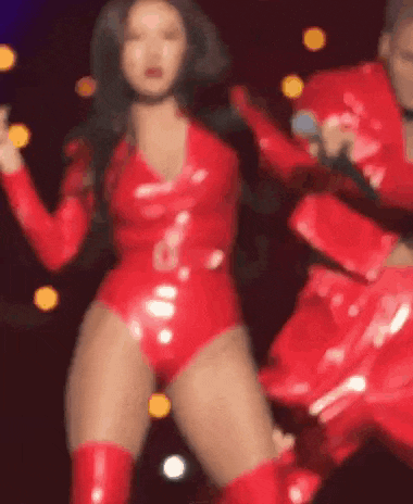 a woman in a red bodysuit and red boots is dancing on a stage with a microphone .