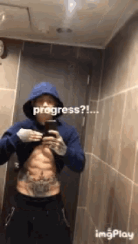 a man in a blue hoodie is taking a selfie in front of a mirror with the words progress written on it