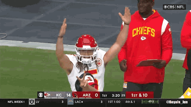 a man wearing a red chiefs sweatshirt stands on the field