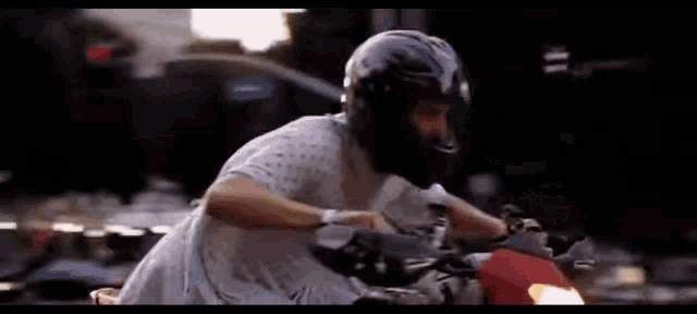 a man wearing a helmet is riding a motorcycle on a city street .