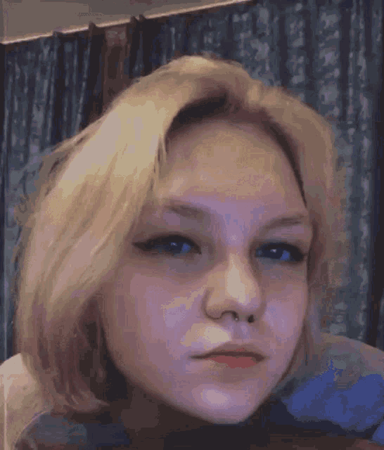 a close up of a woman 's face with blonde hair and blue eyes