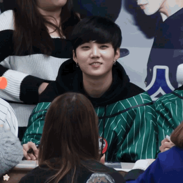 a man in a green and white striped shirt is smiling in front of a crowd