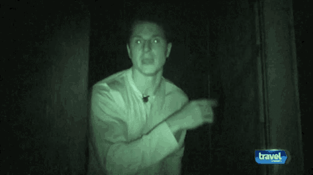 a man in a white shirt is standing in a dark room with a travel channel logo behind him