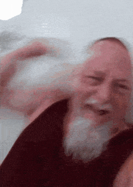 a man with a beard is laying in a bathtub with his eyes closed and smiling .