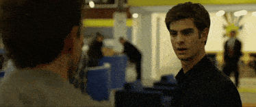 a man in a black suit is looking at another man