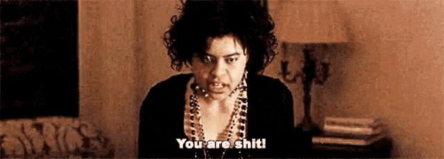 a woman with curly hair is making a funny face and says `` you are shit ! ''