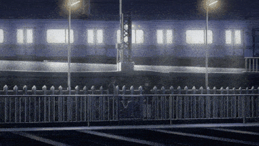a train is going down the tracks at night with a fence in the foreground