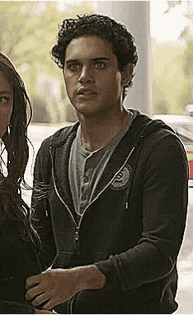 a young man in a black hoodie is standing next to a woman .
