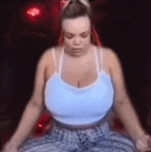 a woman with very large breasts is sitting in a chair with her eyes closed .