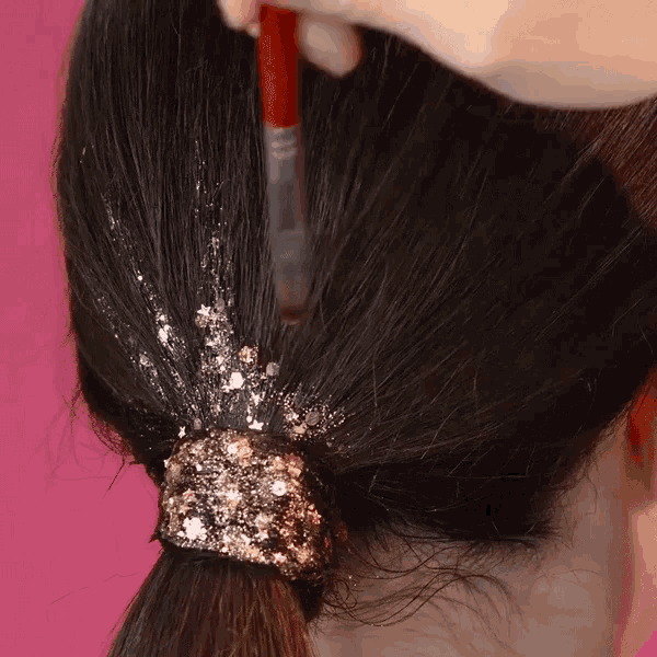 a person is applying glitter to their hair with a brush