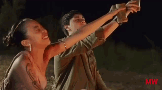 a man and a woman are taking a picture of themselves with their phones .