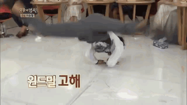 a person is doing a handstand on the floor in a room with tables and chairs