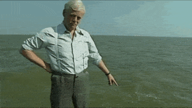 a man in a white shirt and suspenders is standing in the water