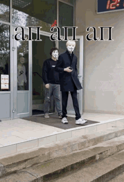 two men wearing face masks are walking down stairs in front of a building with a clock on the wall that reads 12