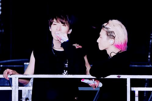 a man with pink hair is holding a microphone and laughing