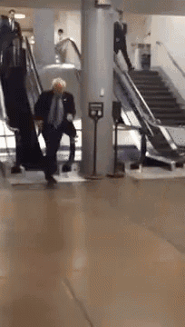 a man in a suit and tie is walking down a set of escalators
