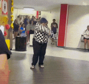 a woman in a checkered shirt is dancing in front of a crowd