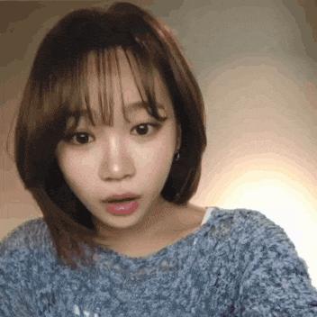 a woman wearing a blue sweater looks surprised