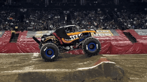 a monster truck on a dirt track with a jcb banner in the background