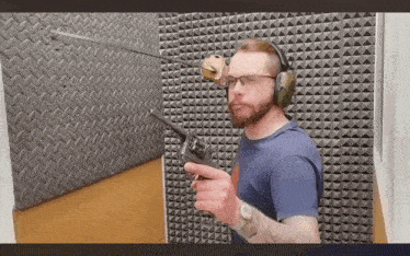 a man wearing headphones and glasses is holding a gun