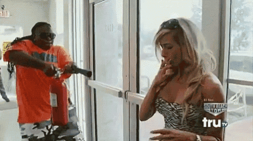 a man is holding a fire extinguisher in front of a woman smoking a cigarette ..
