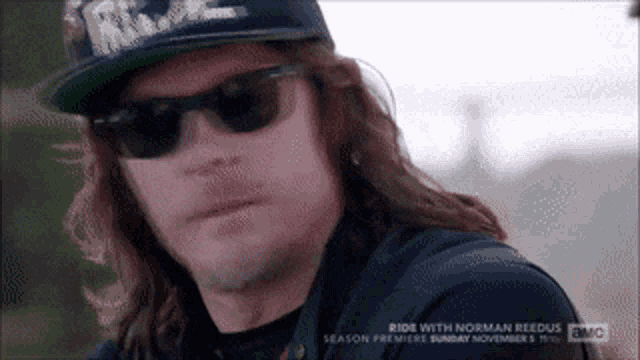 a man with long hair wearing sunglasses and a hat that says ride