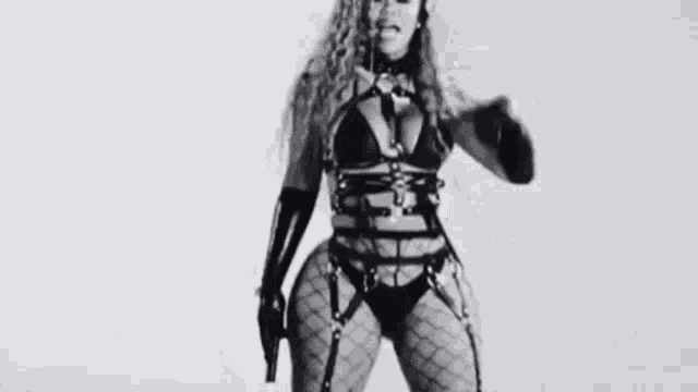 a black and white photo of a woman in a bikini and harnesses holding a gun .