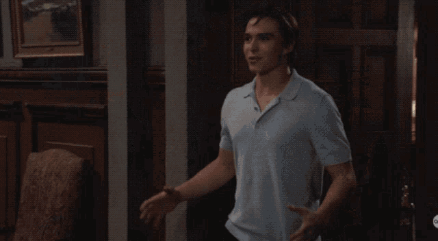 a man in a blue shirt is talking to a woman and a man in a black shirt
