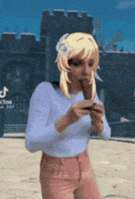 a woman in a white shirt and pink pants is playing a flute in front of a castle .