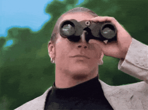a man in a suit looks through binoculars at something