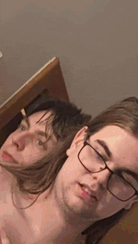 a man and a woman are laying next to each other on a bed with glasses on .