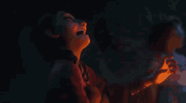 a girl is looking at a lit candle in a dark room