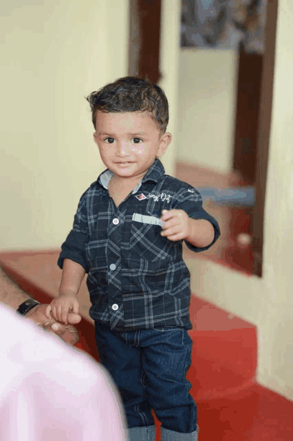 a little boy wearing a shirt that says simply 03 is holding someone 's hand