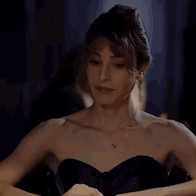 a woman in a black strapless dress with a necklace